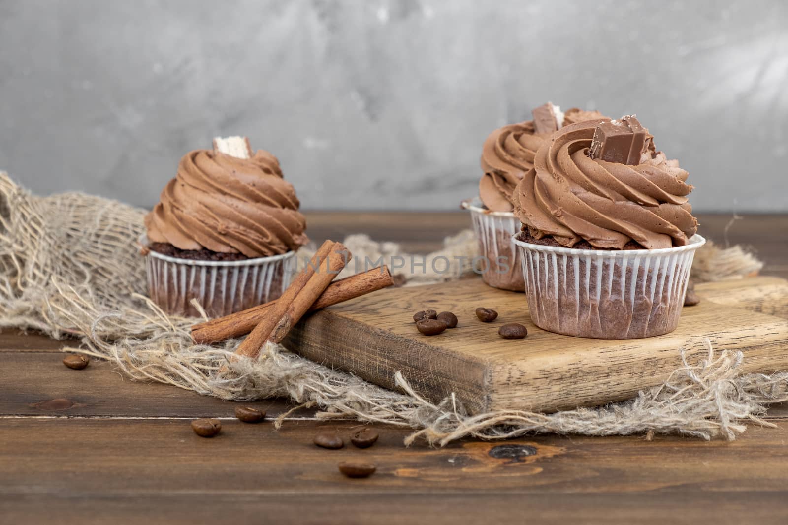 brown cupcakes with cocoa cream, cinnamon and coffee on wooden background by rdv27