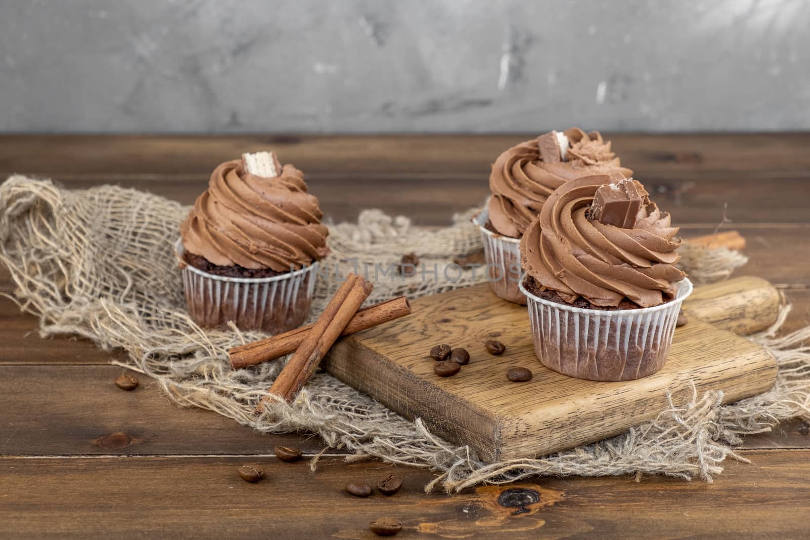 brown cupcakes with cocoa cream, cinnamon and coffee on wooden background by rdv27