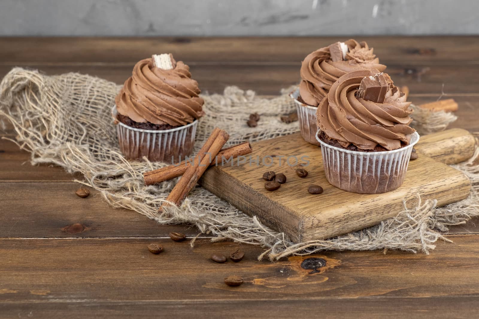 brown cupcakes with cocoa cream, cinnamon and coffee on wooden background by rdv27