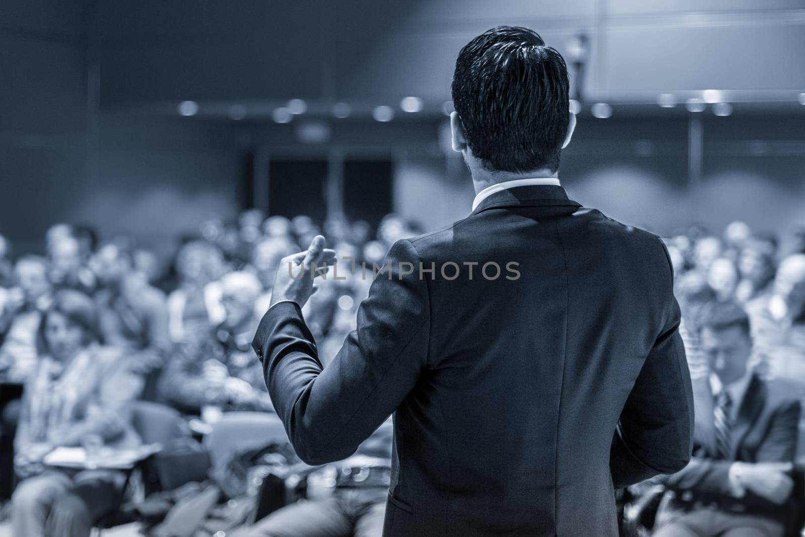 Speaker giving a talk on corporate business conference. Unrecognizable people in audience at conference hall. Business and Entrepreneurship event.