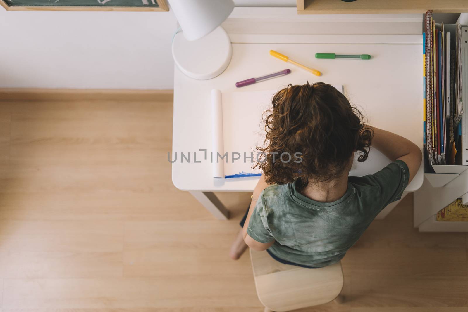 top view of a little girl draws at home with color markers, she is drawing on the table in her room, copy space for text