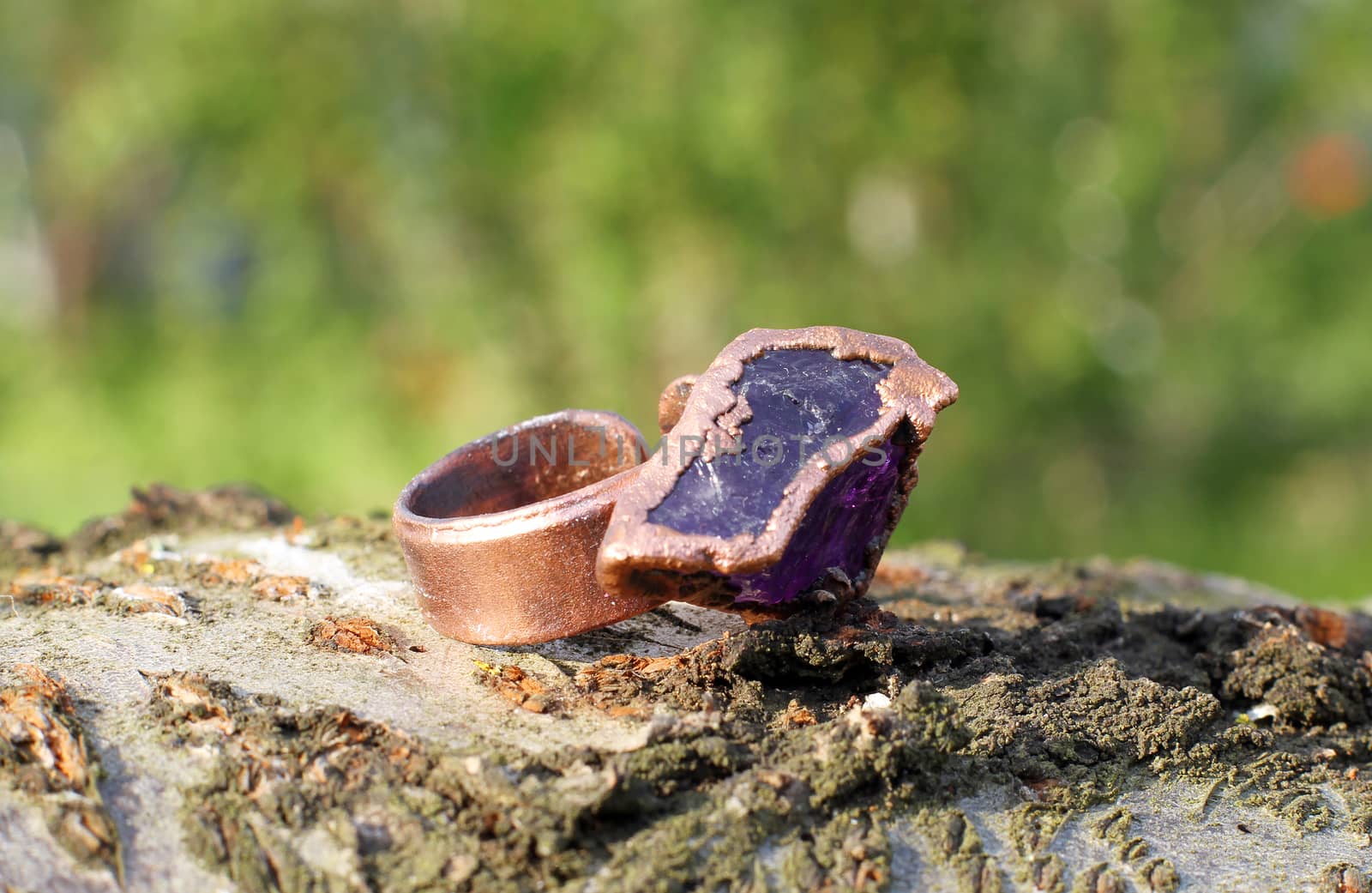 a Hand made copper ring with amethyst on the wooden background