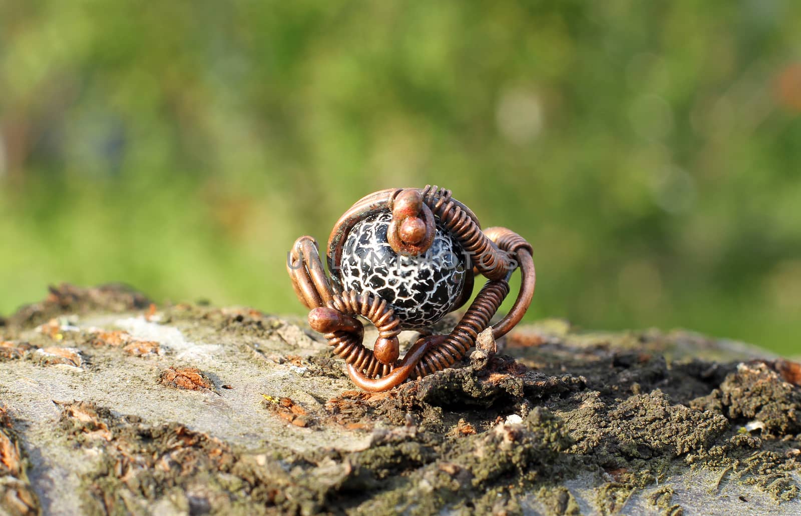 Hand made copper ring with semiprecious stone on the wooden background