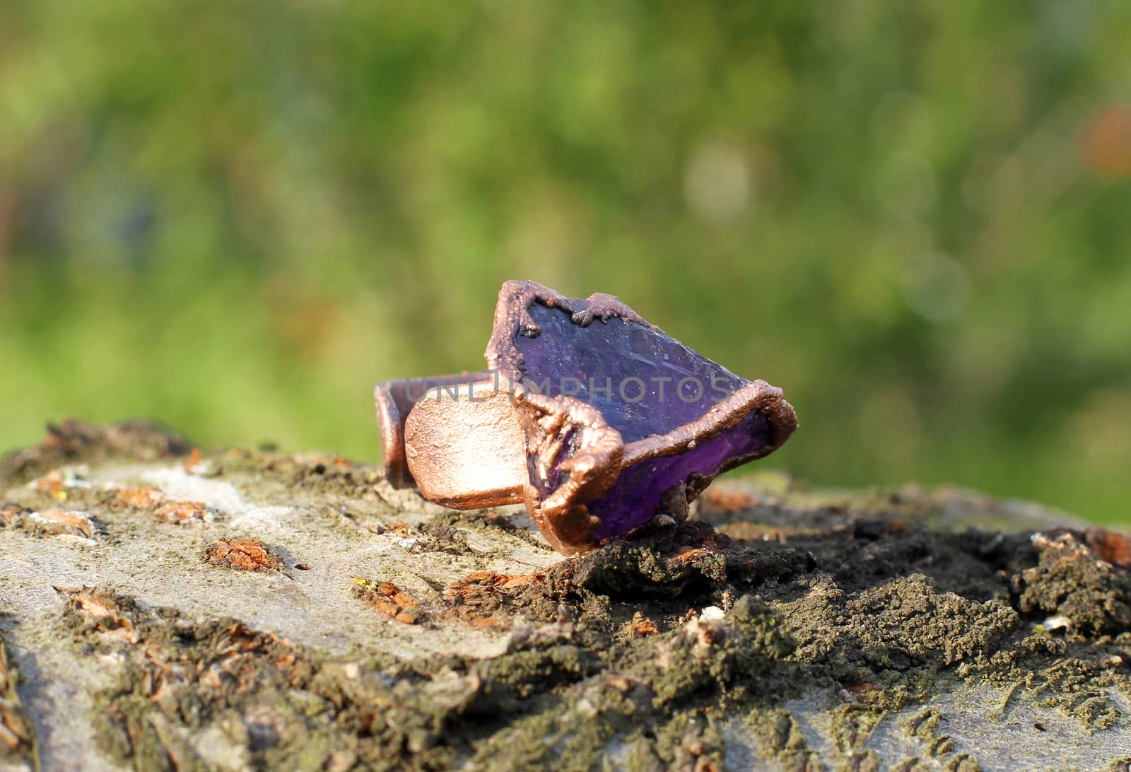 Hand made copper ring with amethyst on the wooden background