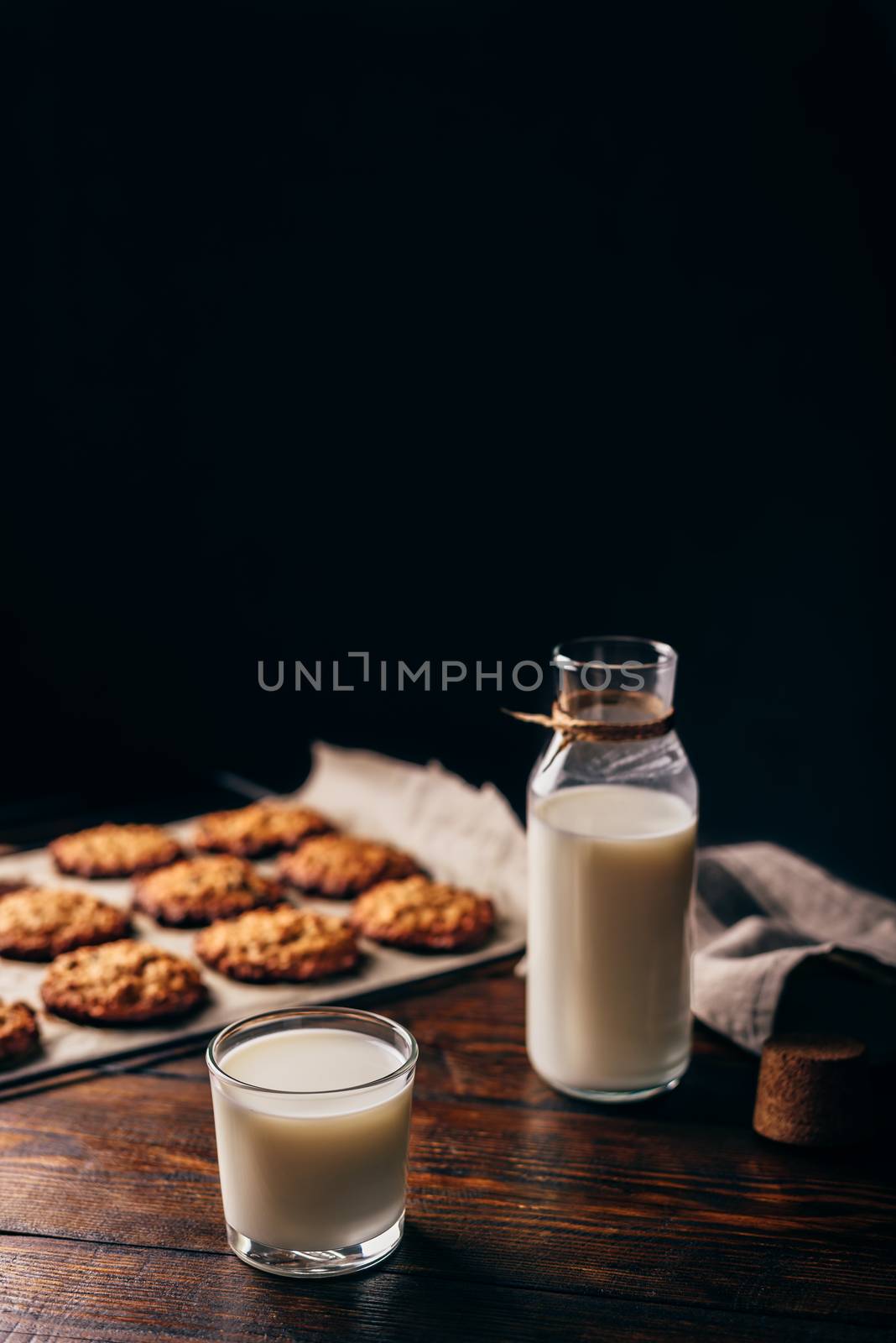 Glass of Milk with Bottle and Oatmeal Cookies on Parchment Paper. Copy Space on the Top.