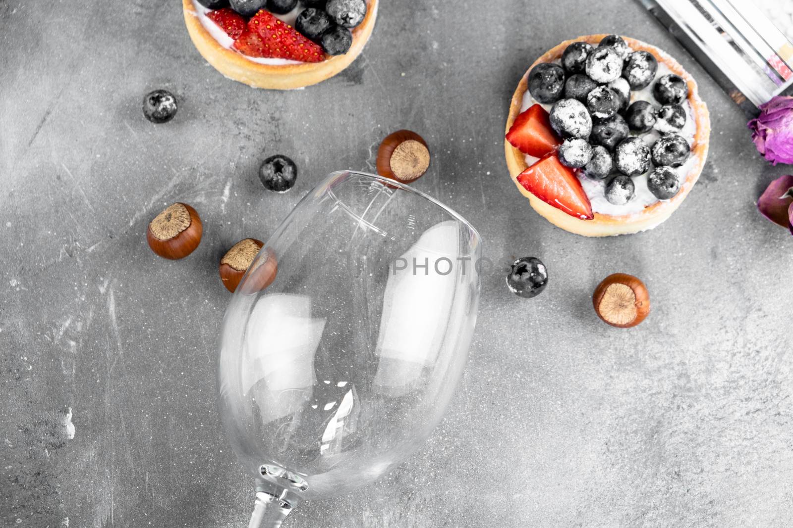 Blueberry and strawberry shortcake. There are hazelnuts, roses and wine corks on the table. Stone gray background.