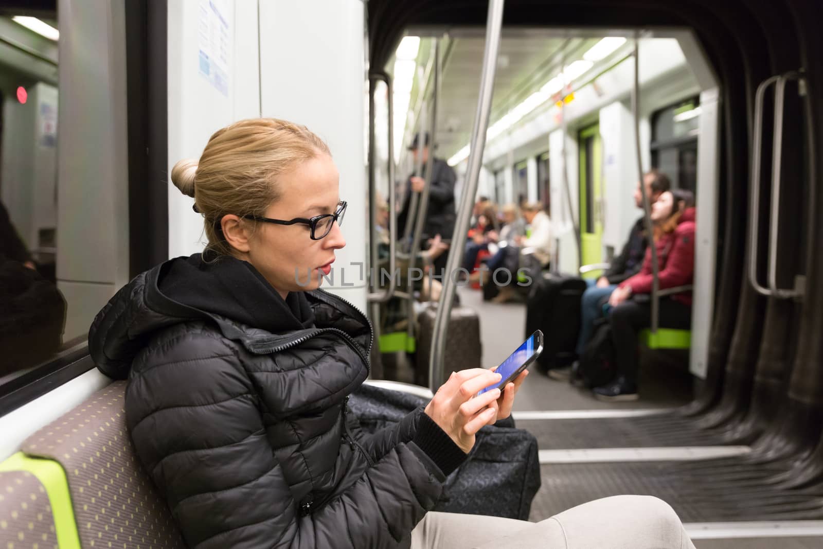 Young girl reading from mobile phone screen in metro. by kasto