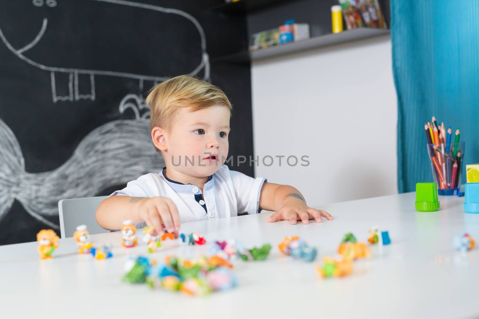 Portrait of cute toddler boy playing with toys at the desk at home. Children learning.