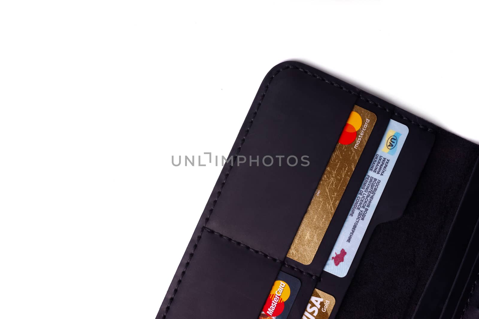 24.01.2019 Ukraine, Kyiv. A part of handmade black leather wallet isolated on white background closeup. A lot of plastic cards in purse pockets. Editorial use only.