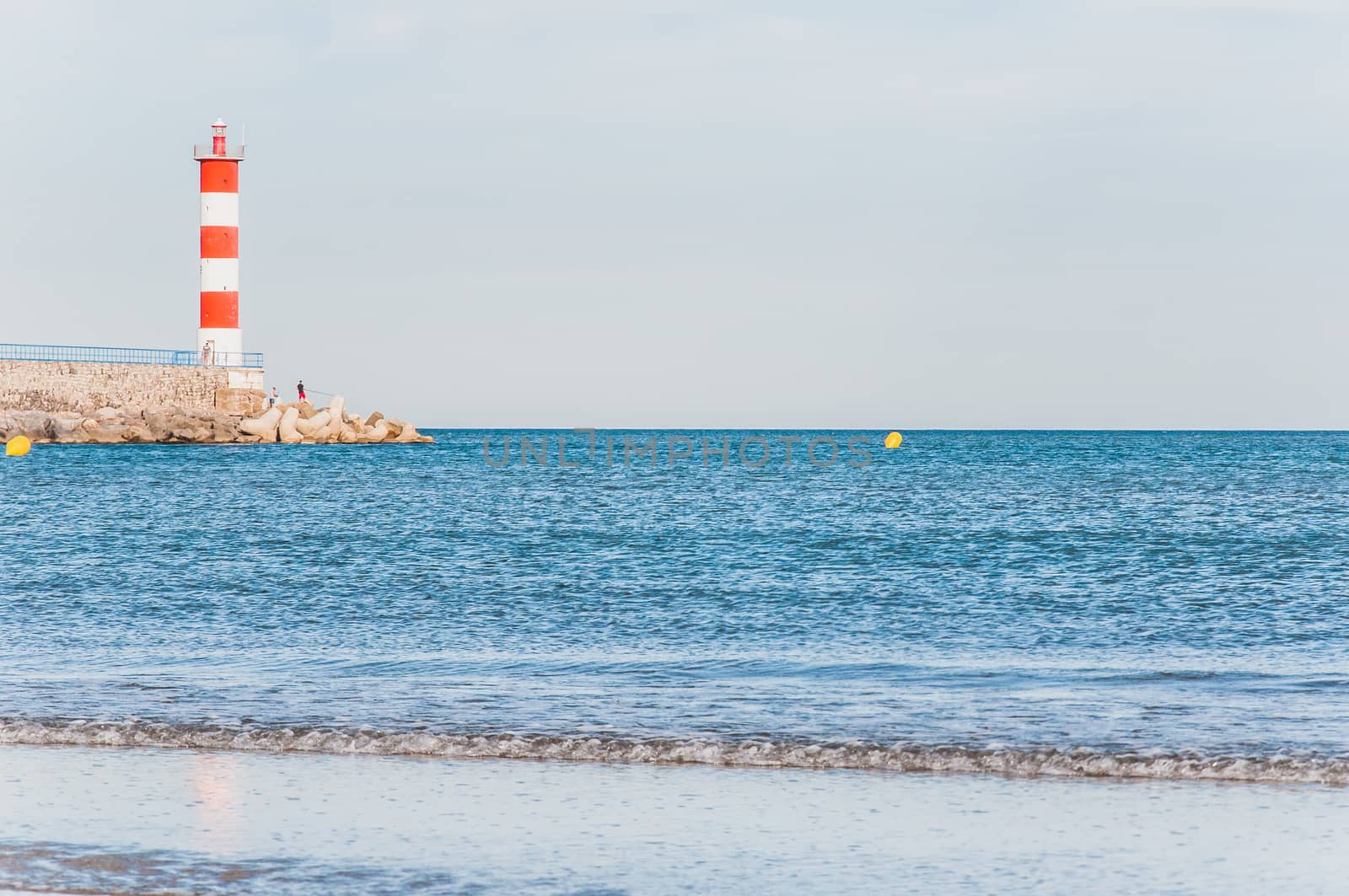 Lighthouse of Port-La-Nouvelle in red and white on cloudy sky in Occitanie, France