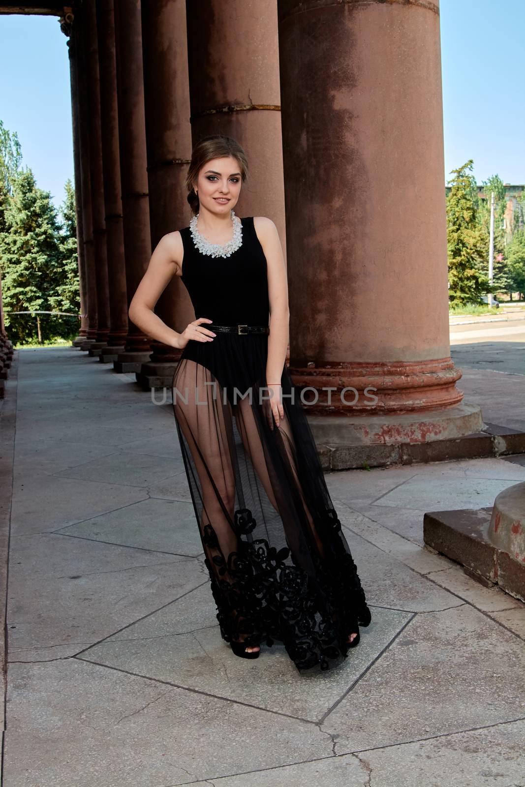 Young woman in sexy transparent black dress near the ancient building. Vintage building. Fashion woman. Young woman modern portrait.