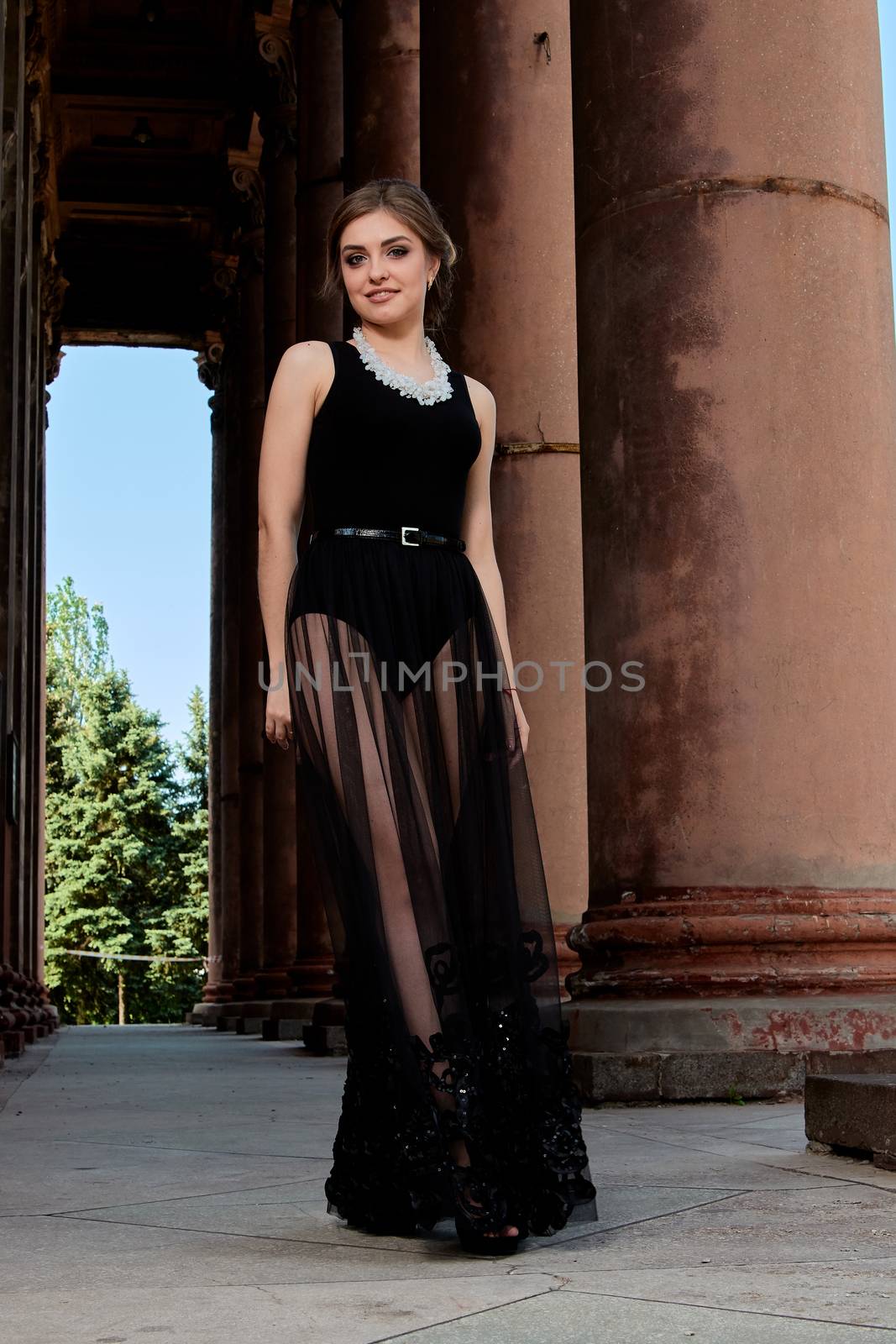 Young woman in sexy transparent black dress near the ancient building. Vintage building. Fashion woman. Young woman modern portrait.