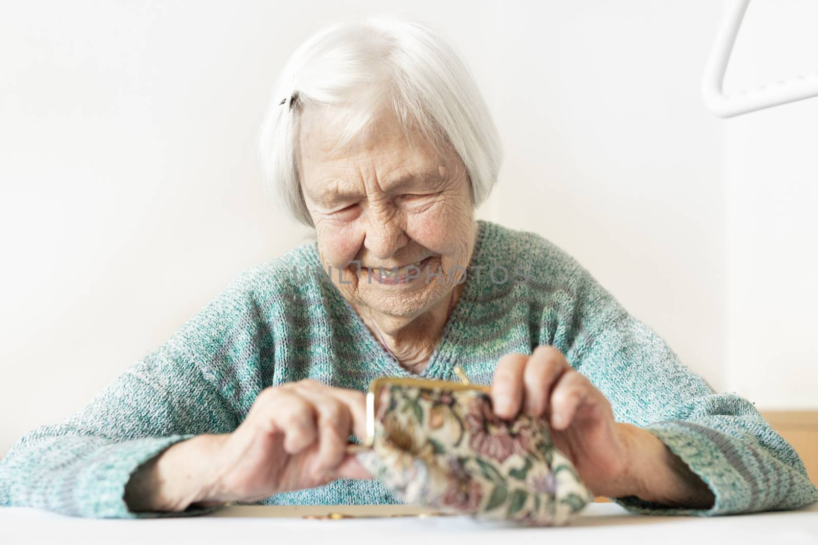 Cheerful elderly 96 years old woman sitting at table at home happy with her pension savings in her wallet after paying bills. Saving for retirement and financial planing concept.