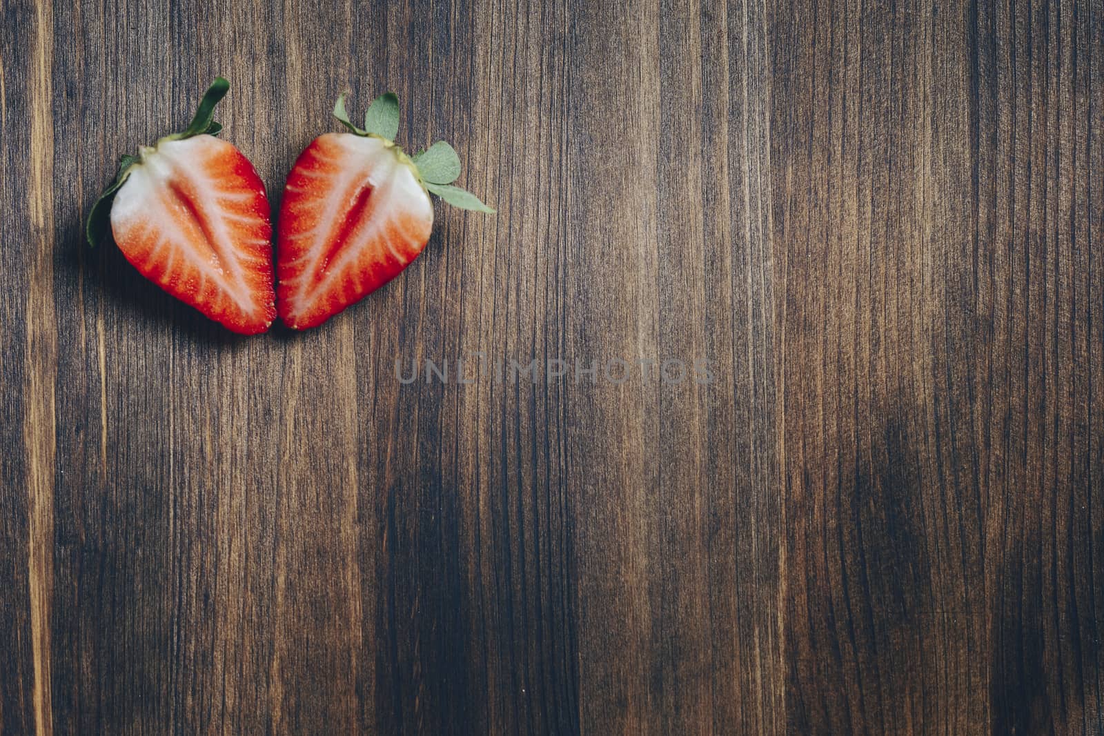 couple strawberry slice cut in half on wooden table in rustic style, healthy sweet food, vitamins and fruity concept. Top view, copy space for text