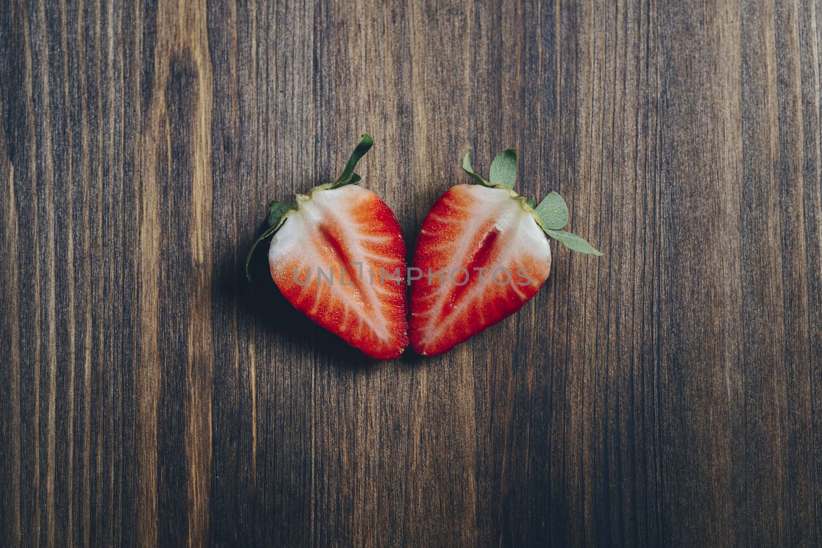 couple strawberry slice cut in half on wooden background in rustic style, healthy sweet food, vitamins and fruity concept. Top view, copy space for text