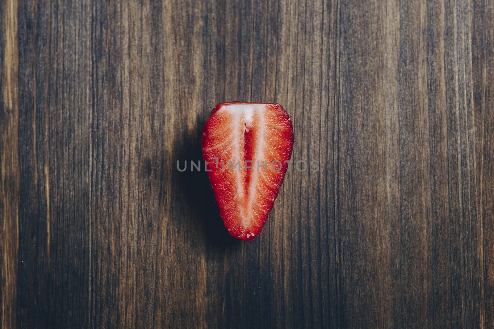 half strawberry on a wooden table in rustic style. Top view, copy space for text