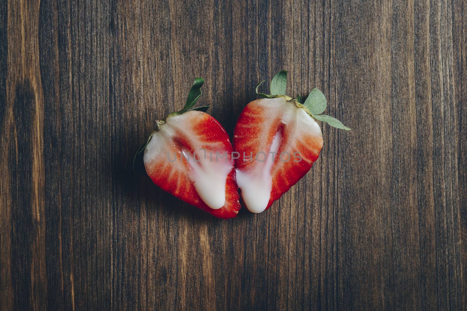 metaphor of sex with strawberries and milk on a wooden background, top view, copy space for text