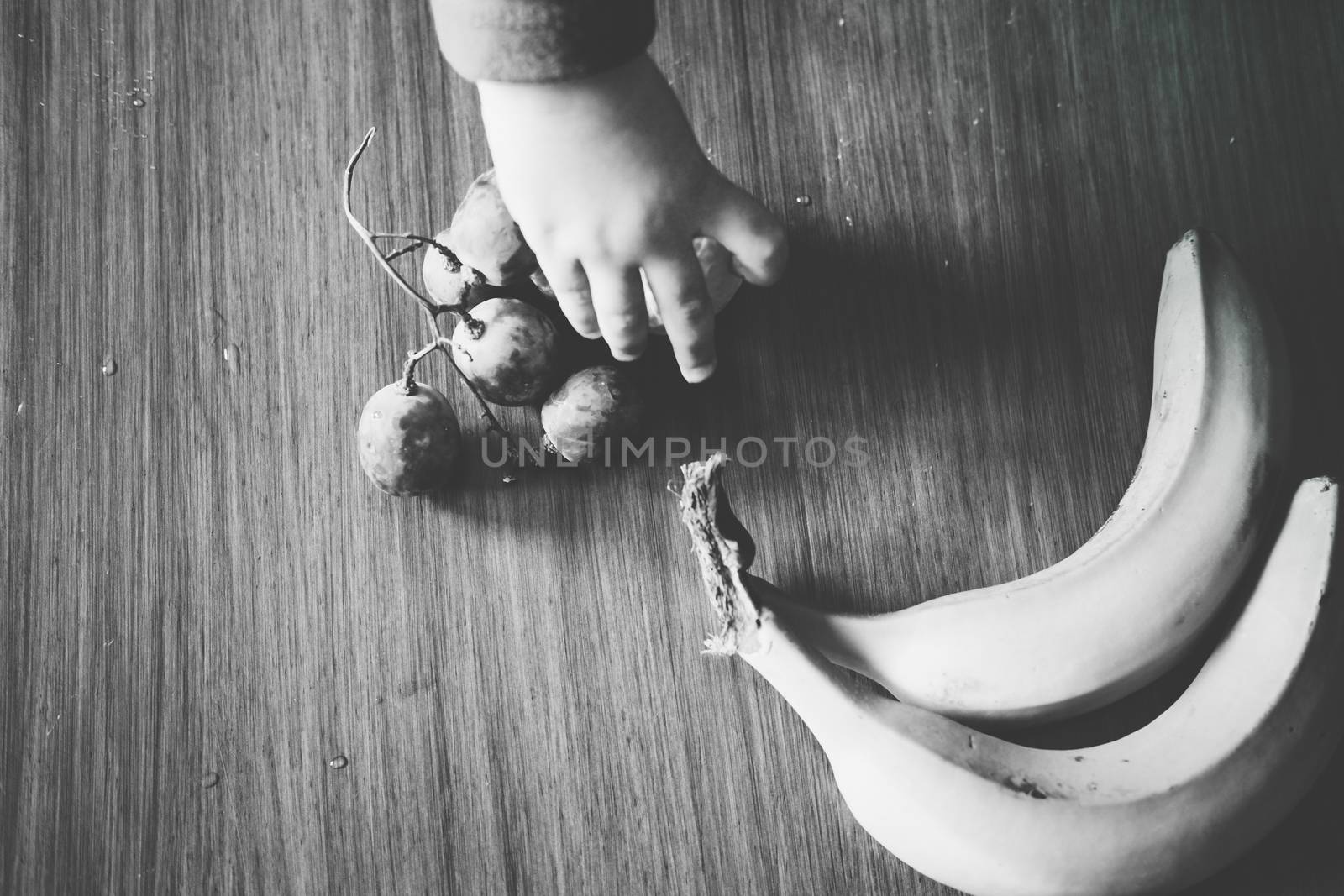 Baby s hand manipulating different fruits on a wooden table by mikelju