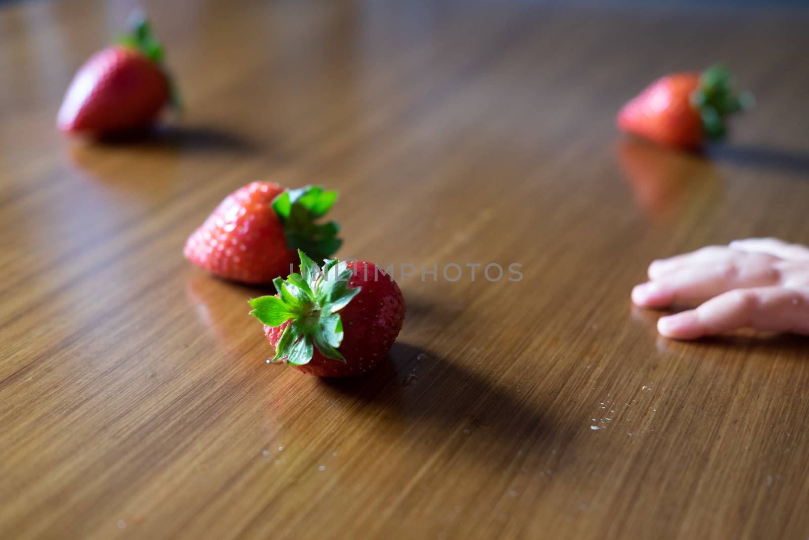 Baby s hand manipulating different fruits on a wooden table by mikelju
