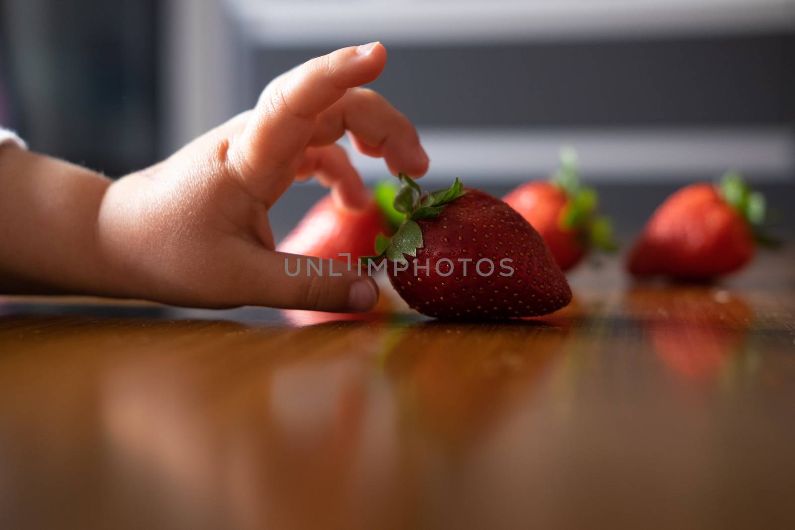 Baby s hand manipulating different fruits on a wooden table by mikelju