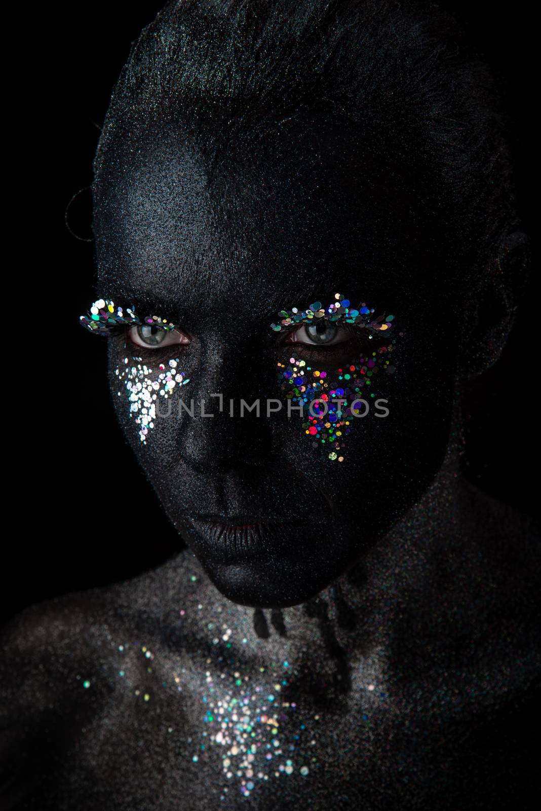 Conceptual art Portrait of Beautiful Woman in Black makeup with Sparkles on a Face isolated on a dark background