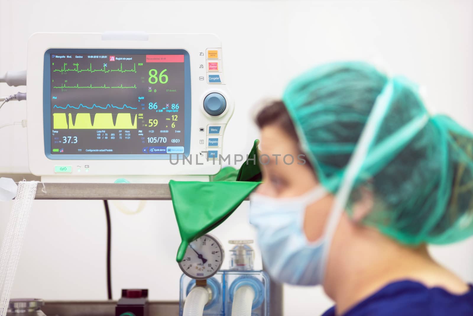 Veterinarian doctor portrait in operating room. Anesthesia monitoring in the background