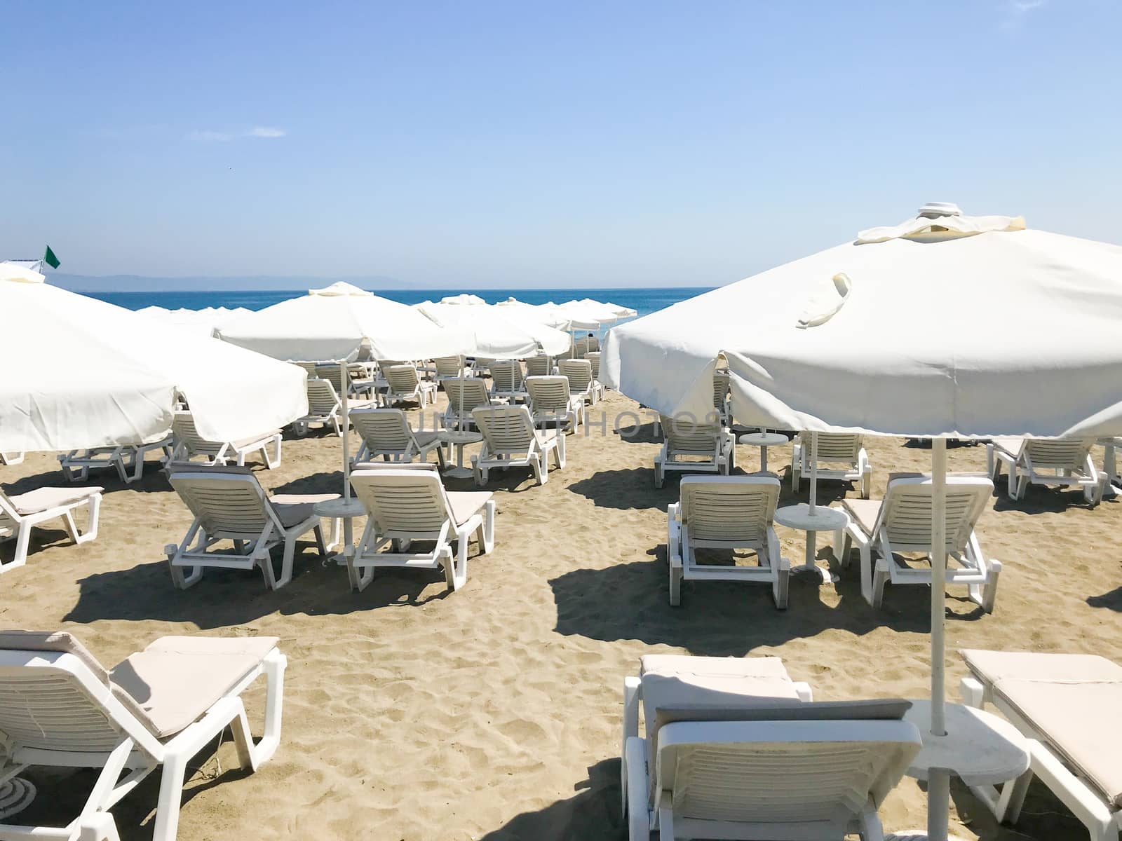 White Loungers And Umbrellas At The Beach In Pomorie, Bulgaria. by nenovbrothers