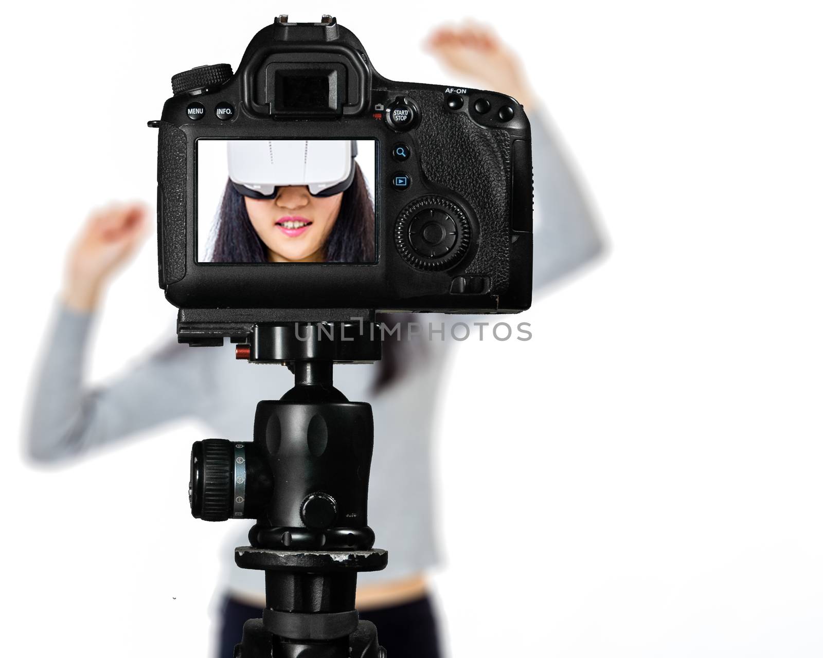 Focus on live view on camera on tripod, teenage girl  using VR goggles image on back screen with blurred scene in background. Teenage vlogger livestreaming show concept