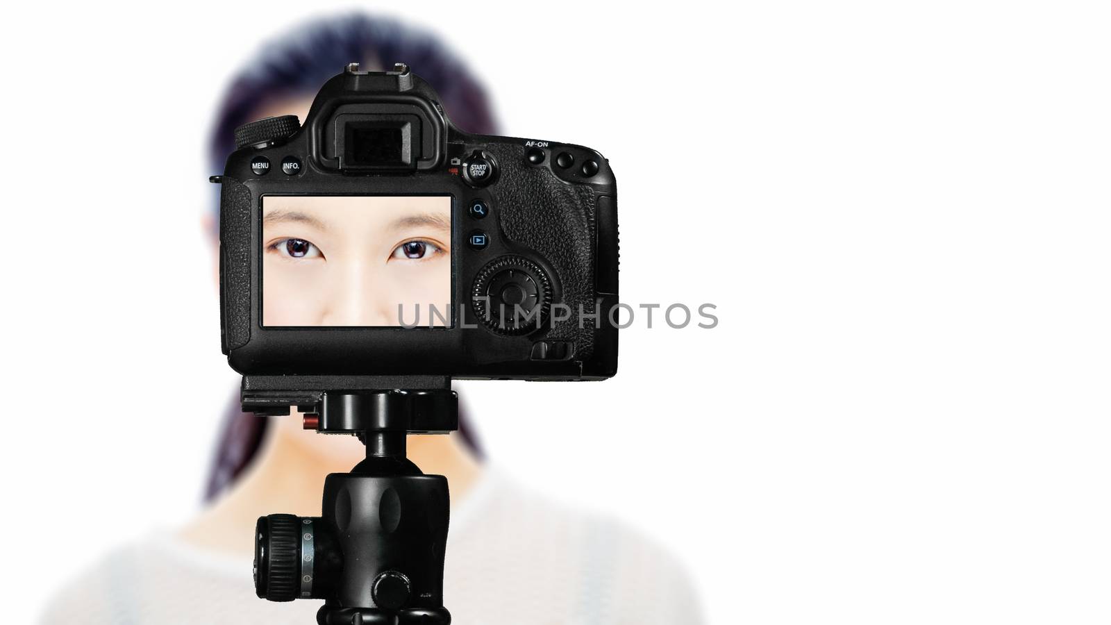 Focus on live view on camera on tripod, teenage girl  beauty shoot image on back screen with blurred scene in background. Teenage vlogger livestreaming show concept