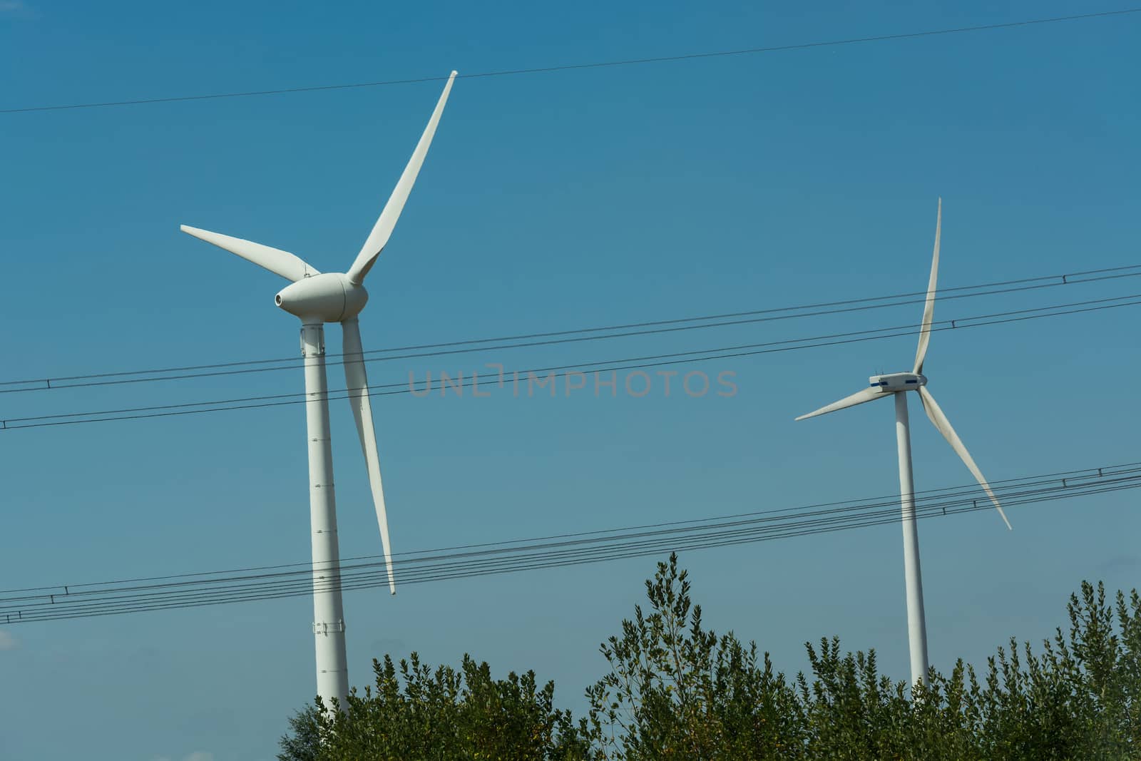 Windmill turbines with partially cloudy blue sky in the background. Wind turbines for renewable energies