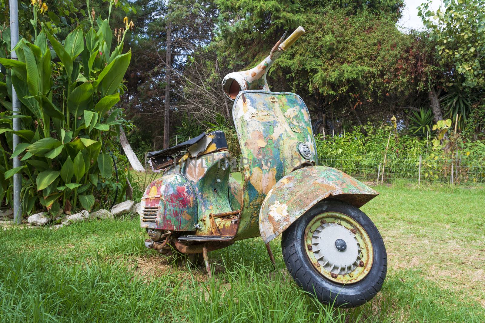 An old abandoned painted motorcycle in a garden at Corfu island, Greece.