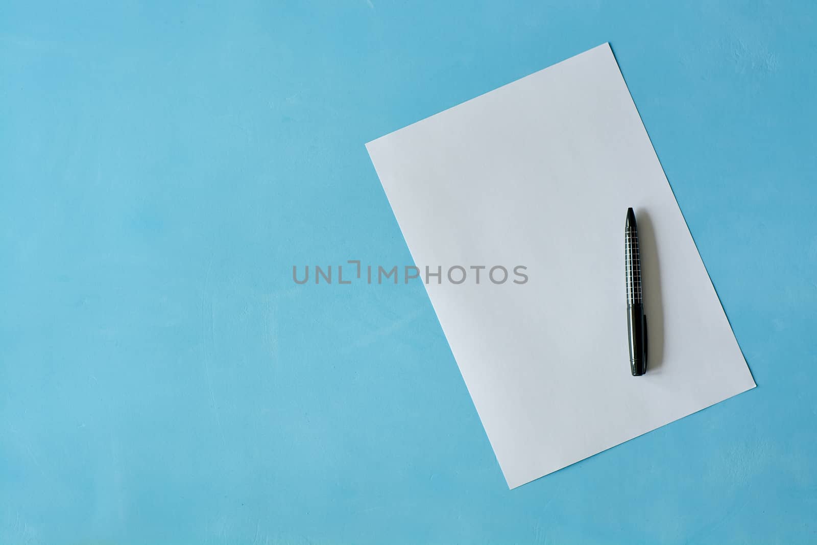 White sheet paper with black pen on blue background with copy space for text. Print disign consept.