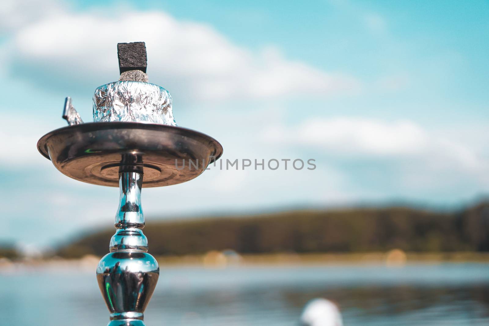 Summer vacation, activity. environment, travel and hookah smoking concept. Hookah bowl stands in nature by the river close up