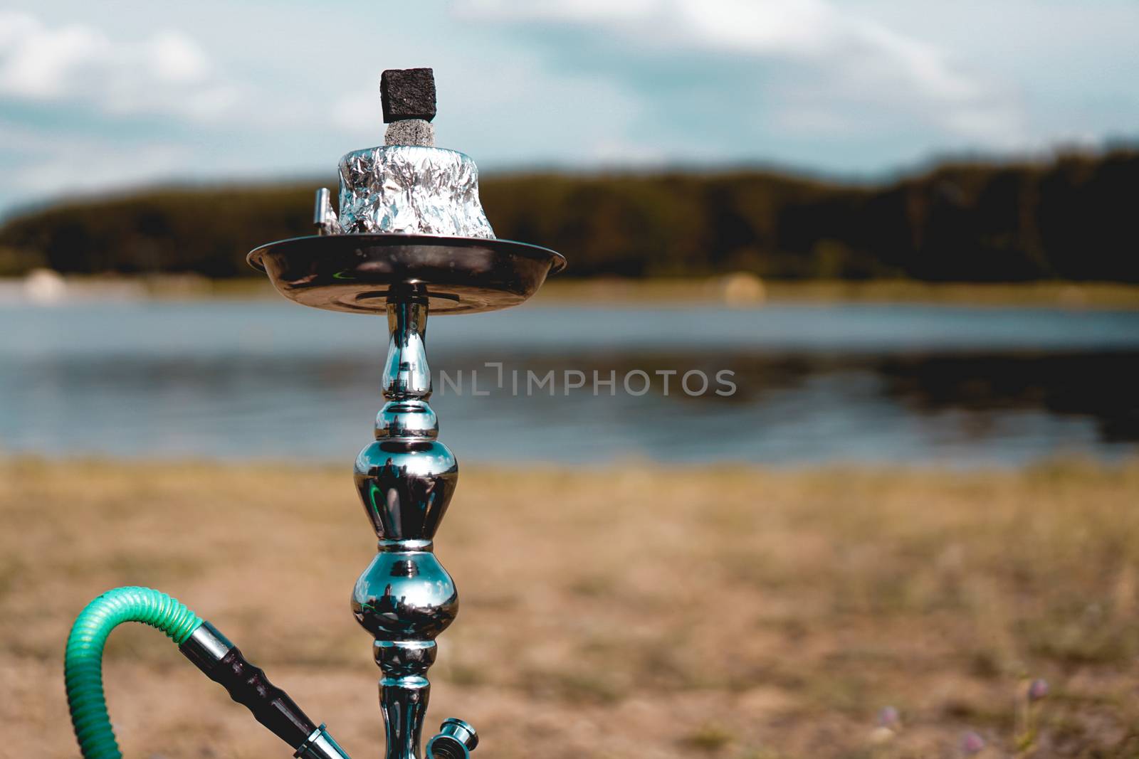 Summer vacation, activity. environment, travel and hookah smoking concept. Hookah bowl stands in nature by the river close up