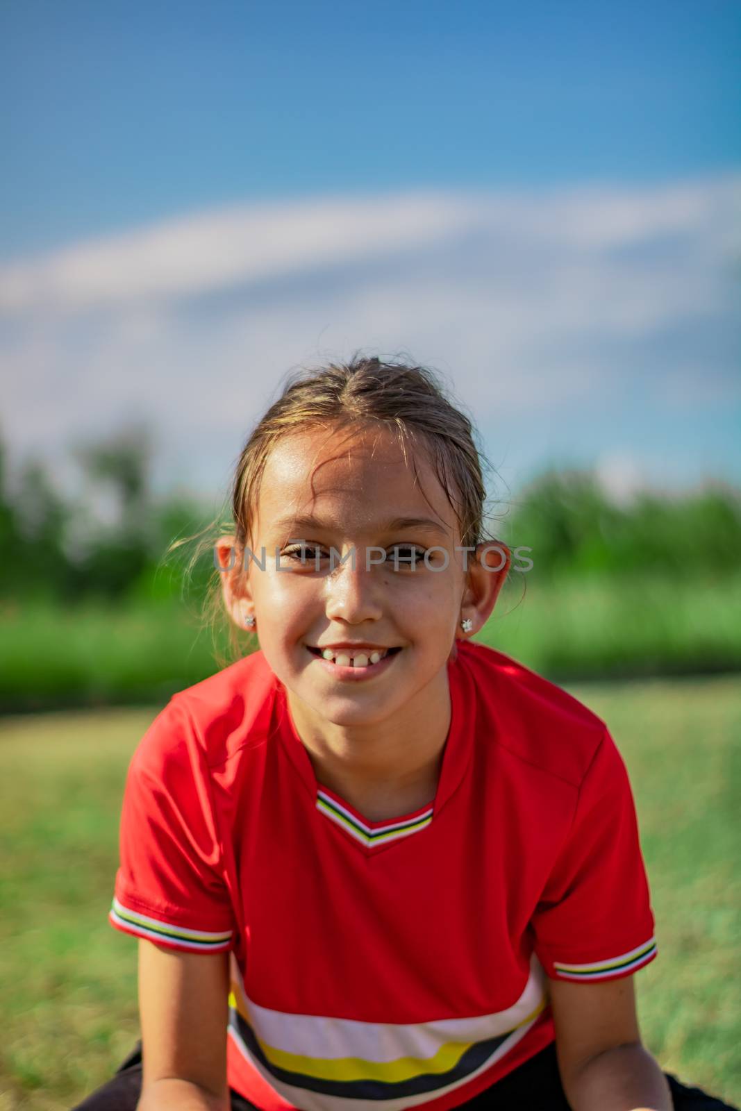 Little girl playing soccer on grassy esplanade