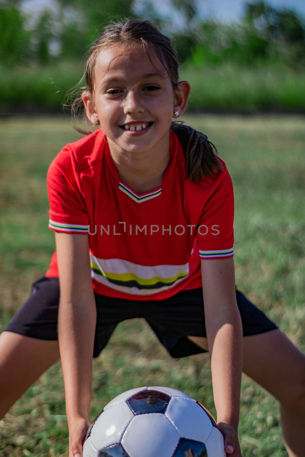 Little girl playing soccer on grassy esplanade