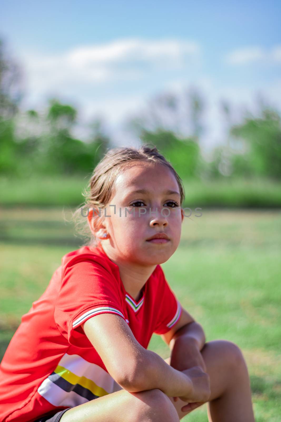 Little girl playing soccer on grassy esplanade