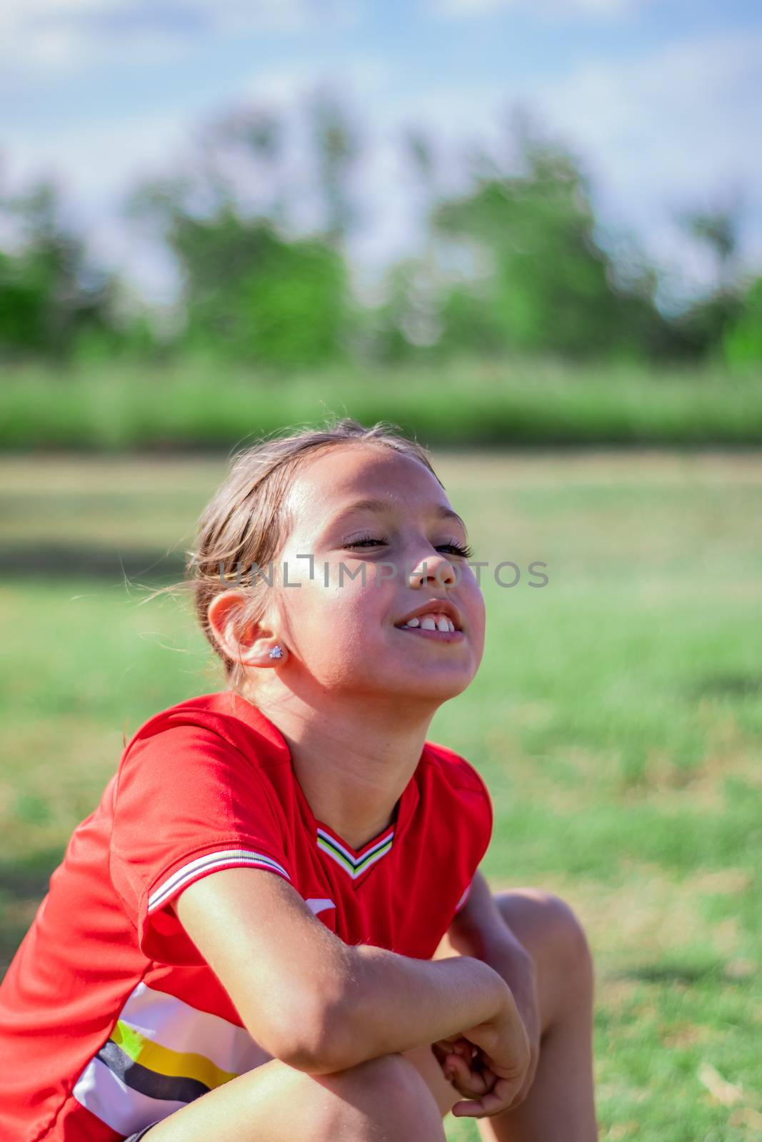 Little girl playing soccer on grassy esplanade