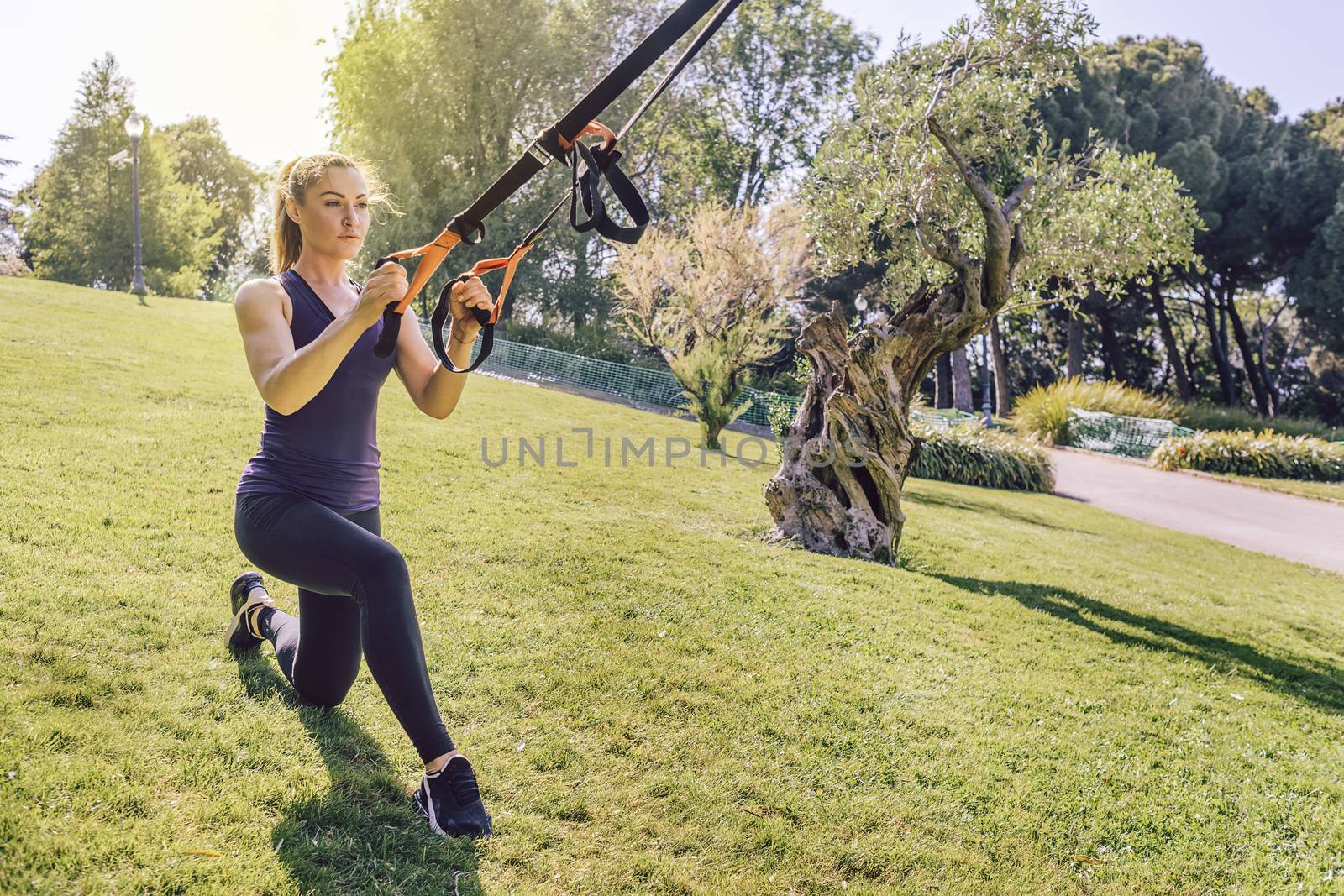 attractive young woman doing fitness and training with suspension straps, she is outdoors during functional workout
