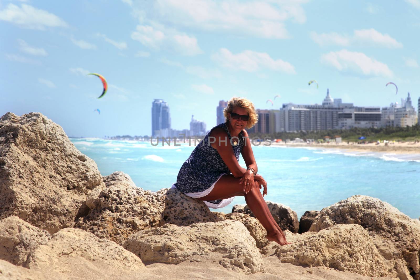 The girl sits on a stone against the backdrop of Miami Beach