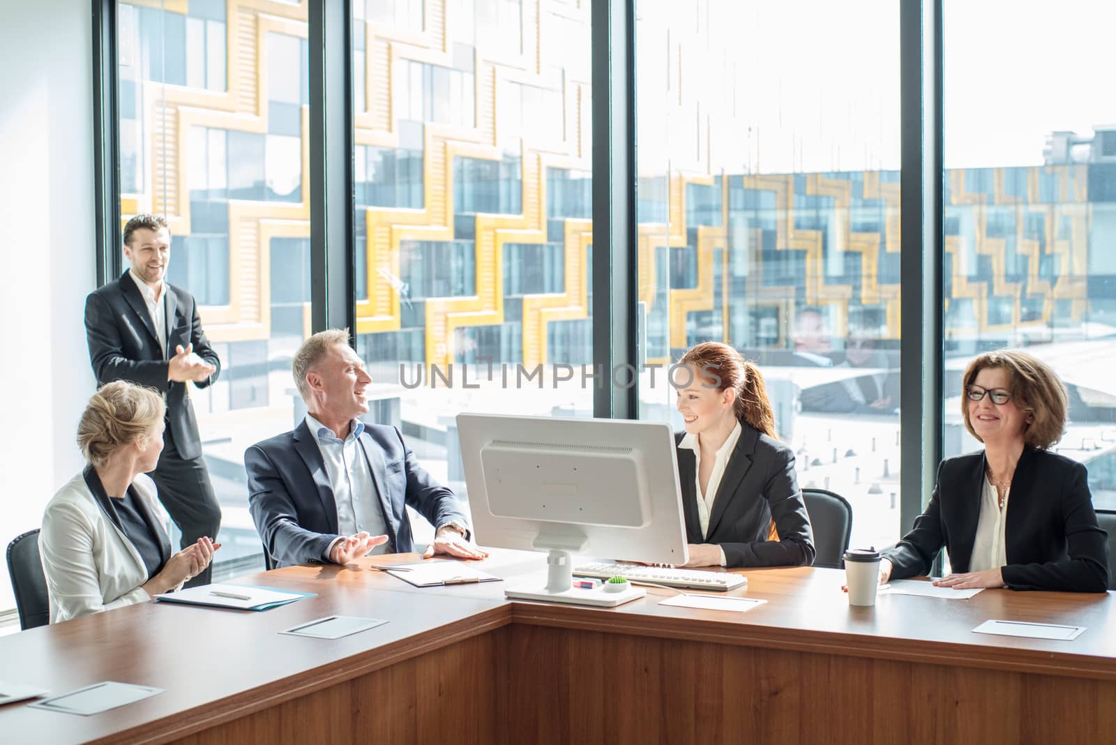 Image of happy smiling business partners discussing documents and ideas at meeting