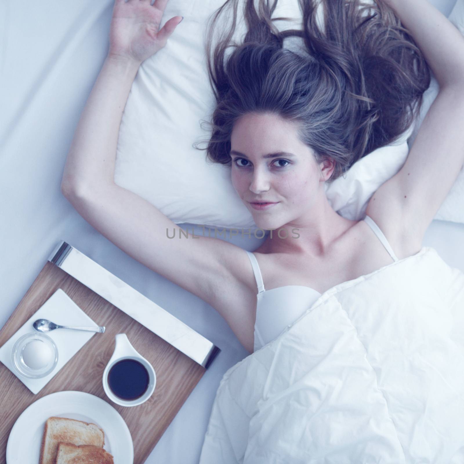 Beautiful young woman having breakfast in bed