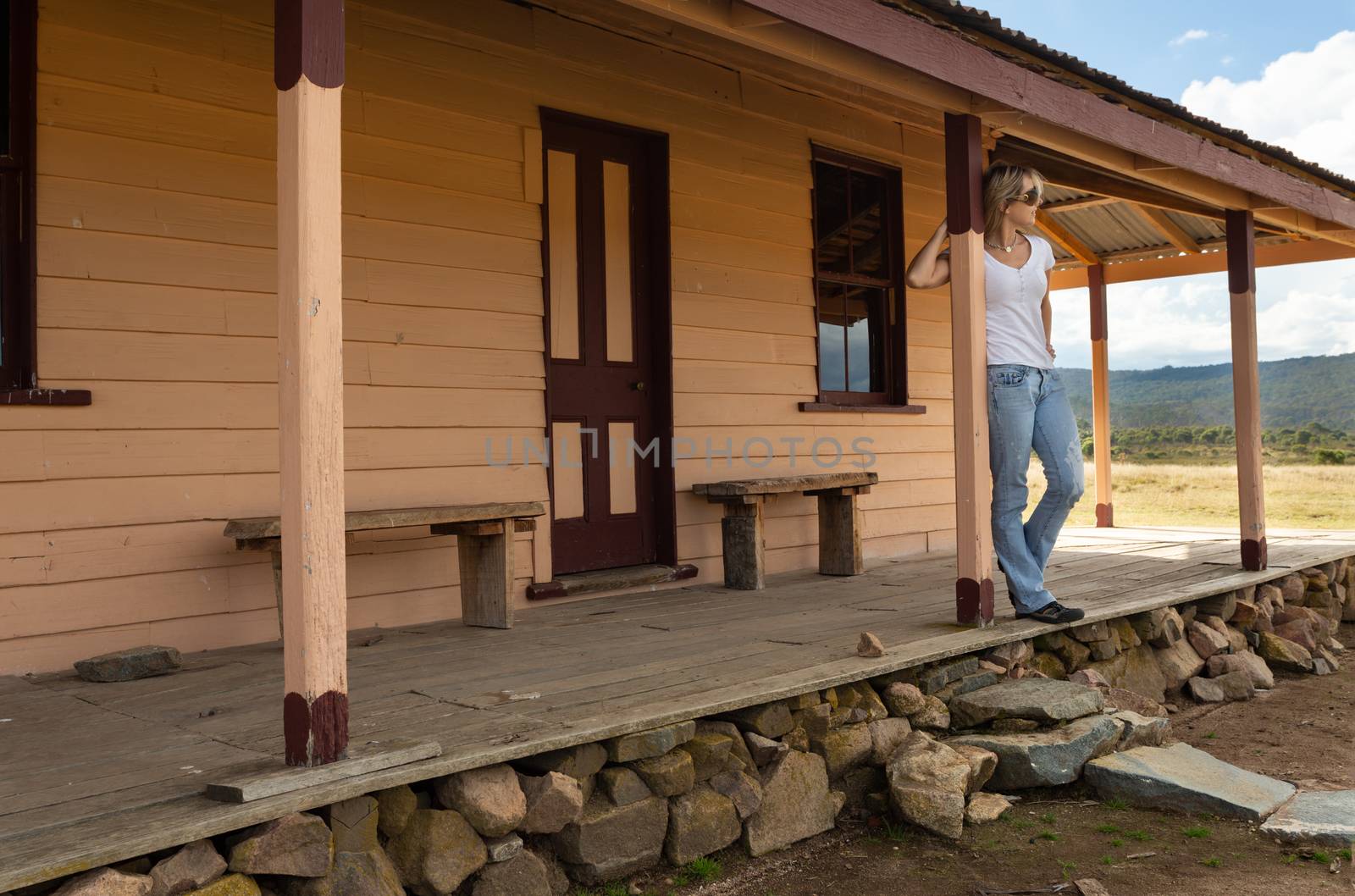 Happy relaxed female on verandah of old timber home in the rural countryside by lovleah