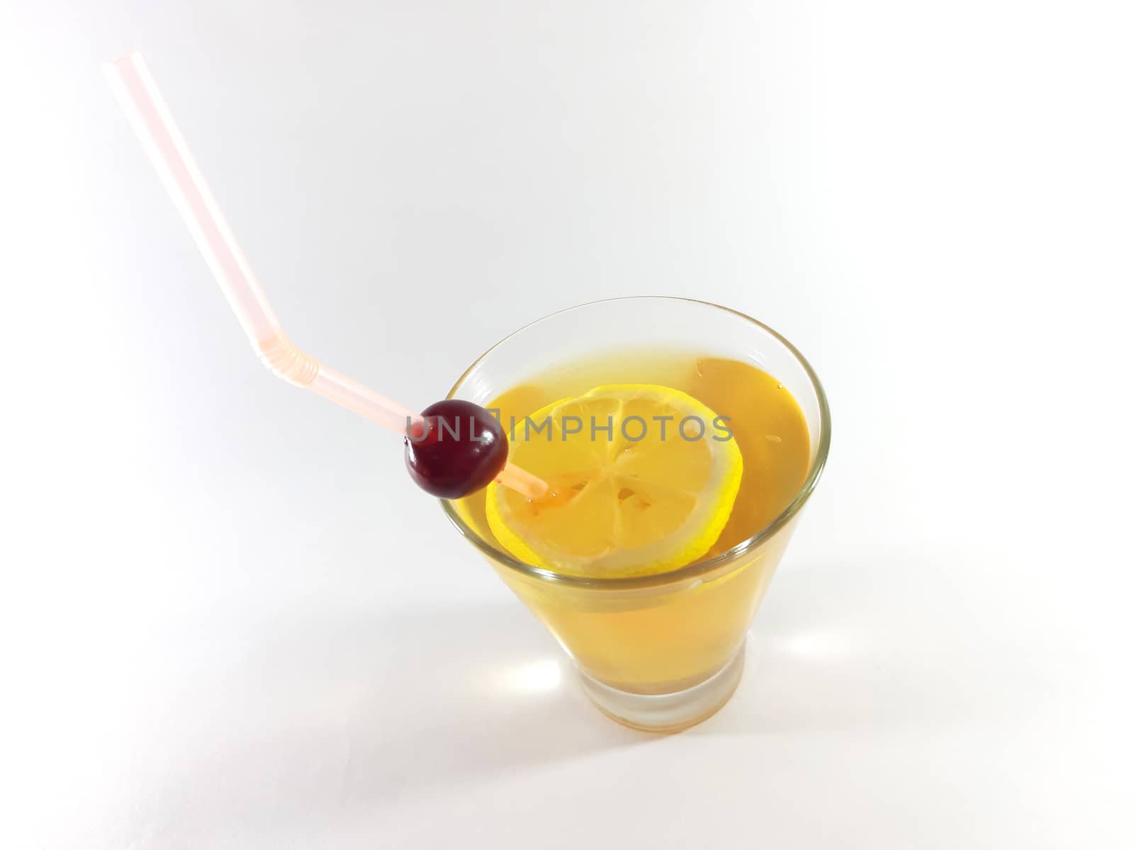 Drink with fruit in transparent container. Lemon and cherry for a snack. Yellow liquid in a glass. Photo for modern design. 
