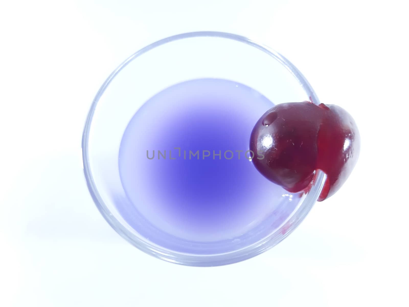 Drink with fruit in transparent glass. Cherry for a snack. Violet liquid in a glass. Photo