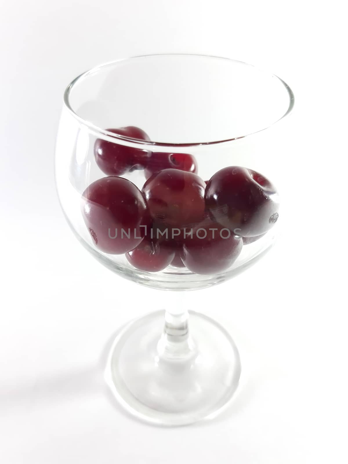 Cherry fruit in transparent wineglass. Cherry for a snack. Photo isolated.