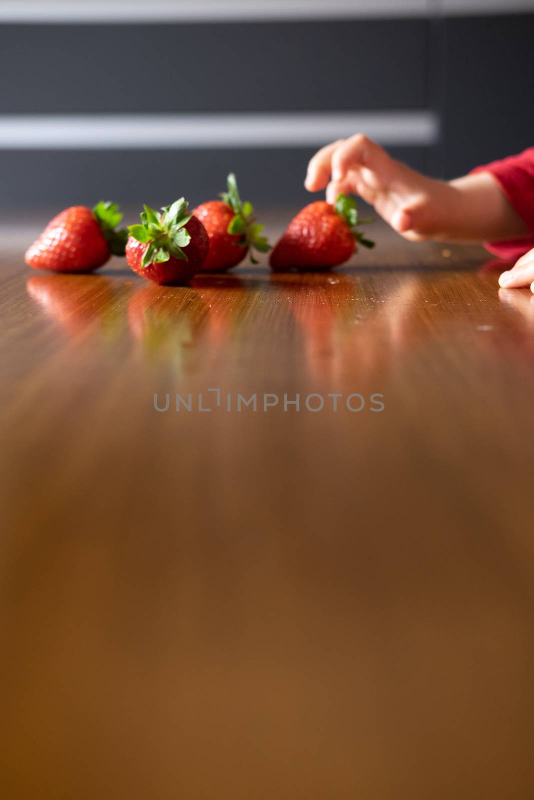 Baby�s hand manipulating different fruits on a wooden table by mikelju