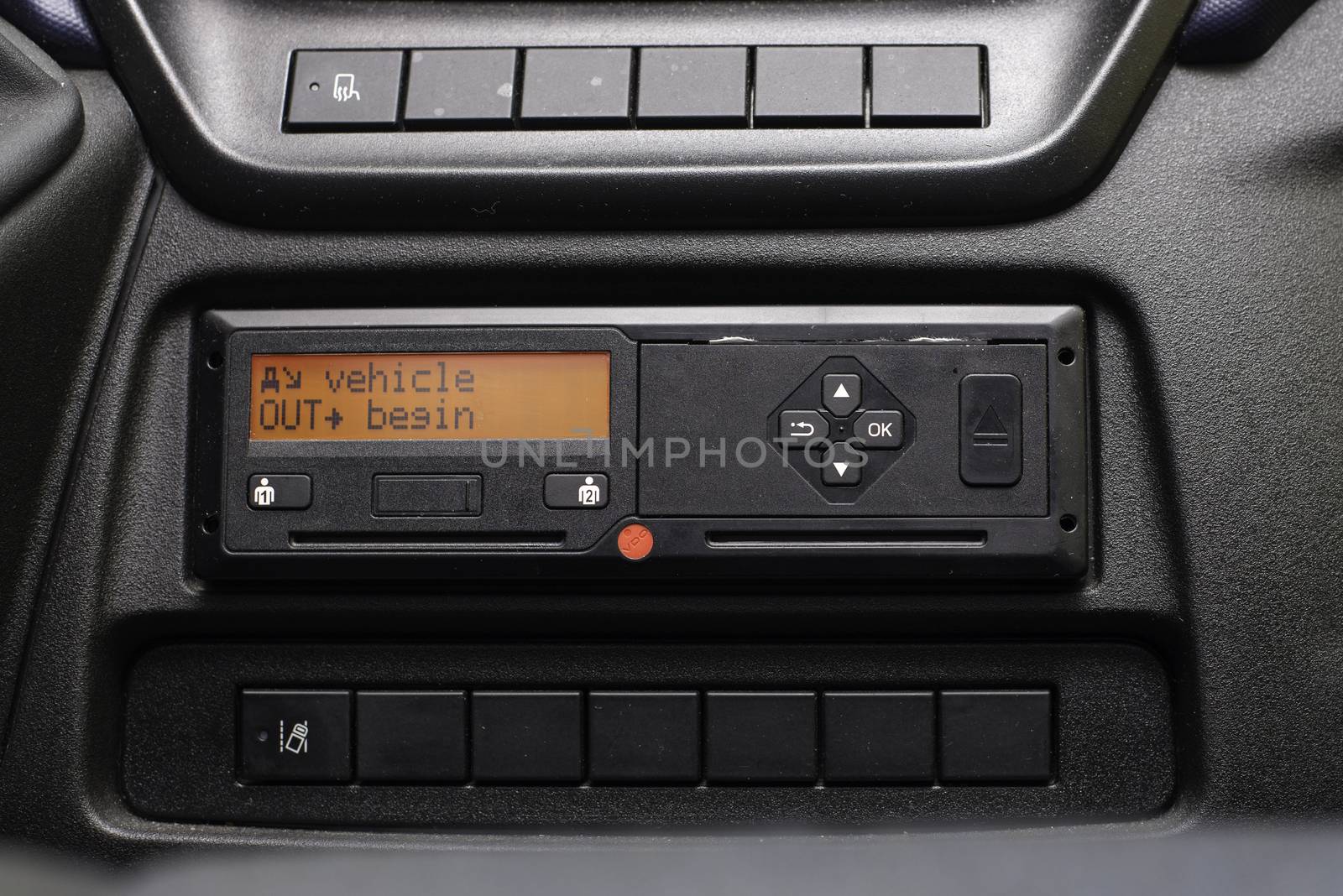 Digital tachograph display reads Vehicle Out Begin. No personal data. Tachograph in a van.