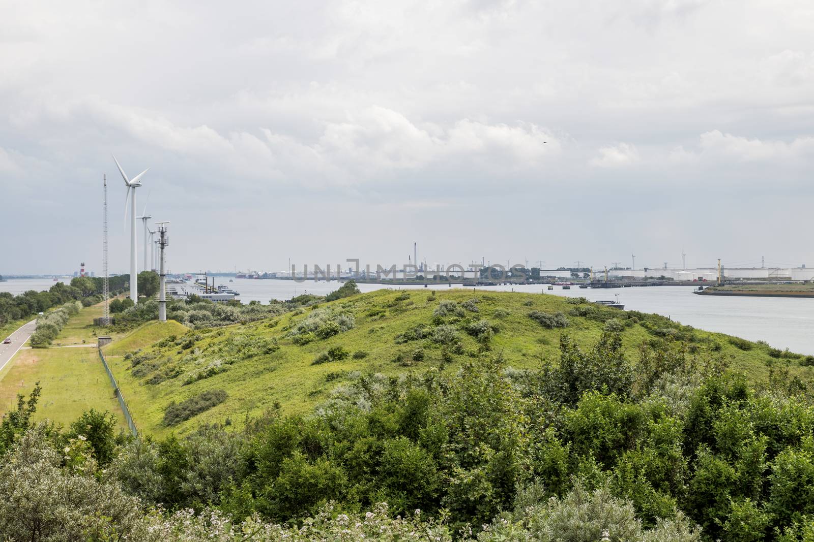 the harbor of rotterdam from the green dunes with the refinery and industry as background