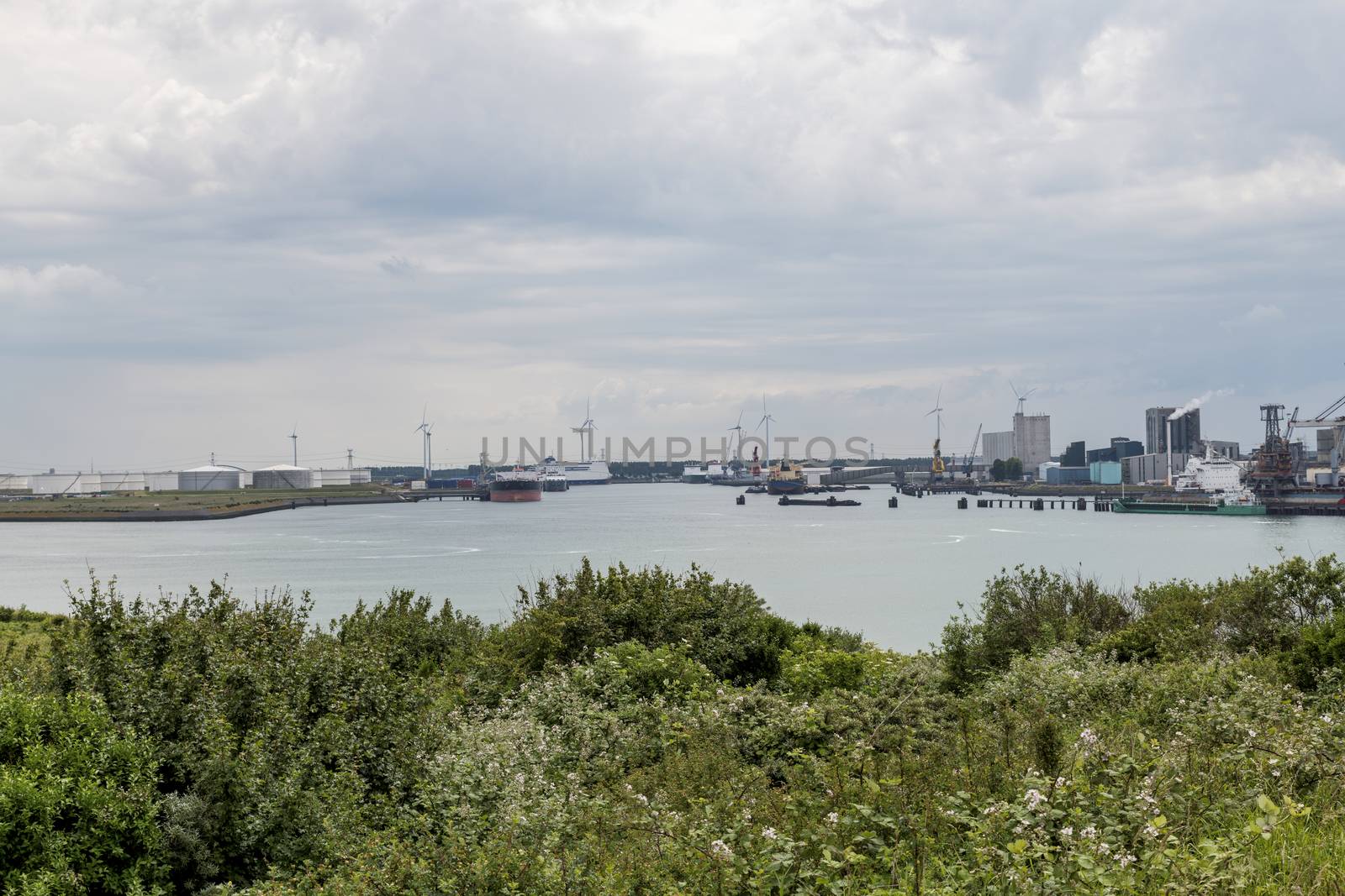 the harbor of rotterdam from the green dunes with the refinery and industry as background